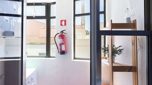 A hotel room with a washing machine, a fire extinguisher, and a wooden chair by the window. - Downtown Lovely Flat by HostWise (Porto)