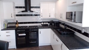 A modern kitchen with white cabinets, a black stove, and a microwave.