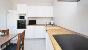 Een kleine keuken met witte kastjes, een magnetron, een oven en een spoelbak.