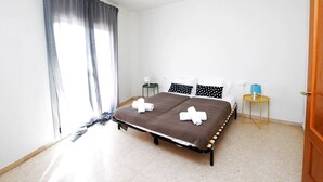 Een hotelkamer met een bed, een klein nachtkastje, een lamp en een raam met gordijnen.
