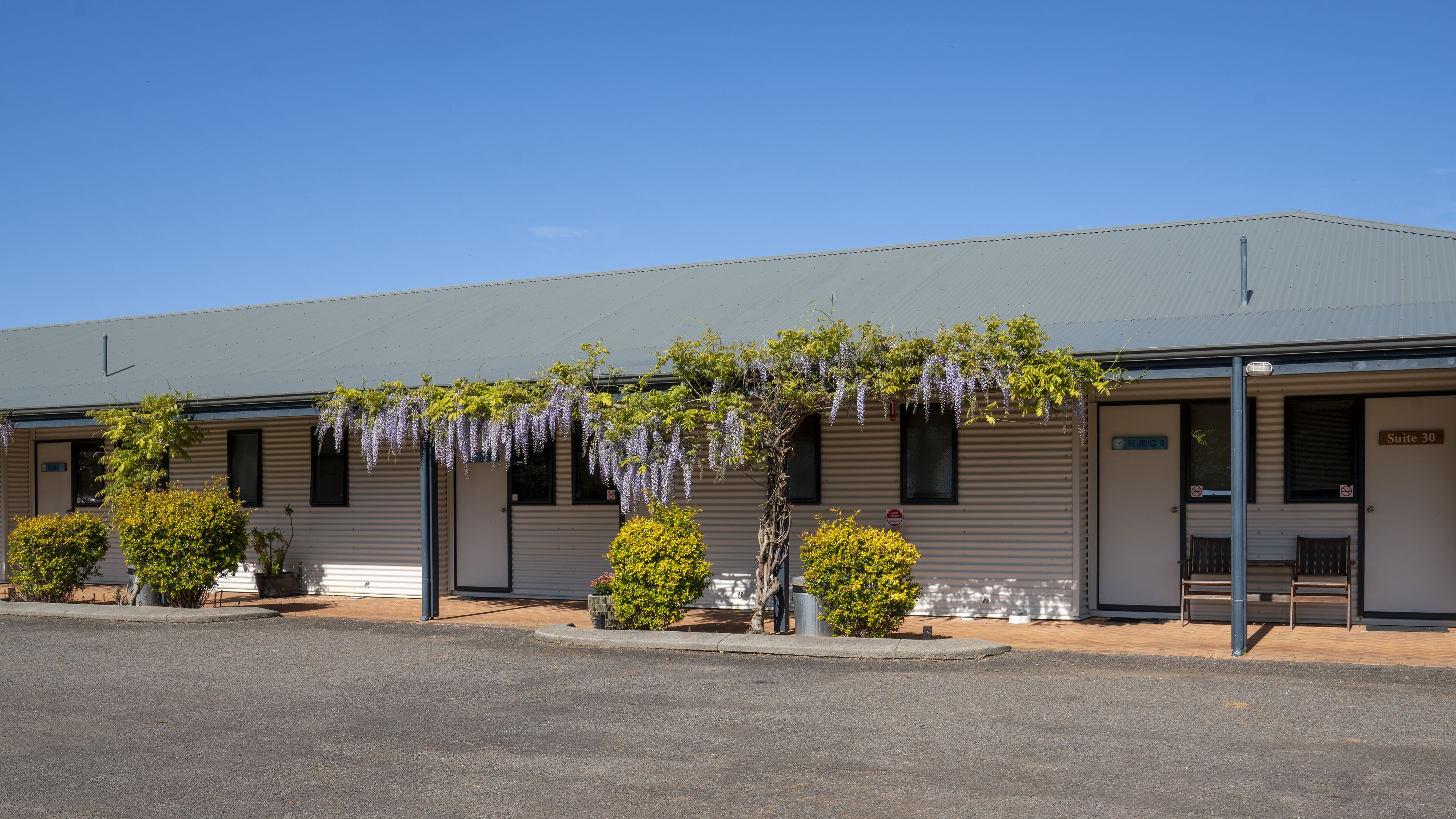 A building with a corrugated metal exterior, a flat roof, and a sign indicating 'Suite 30'.
