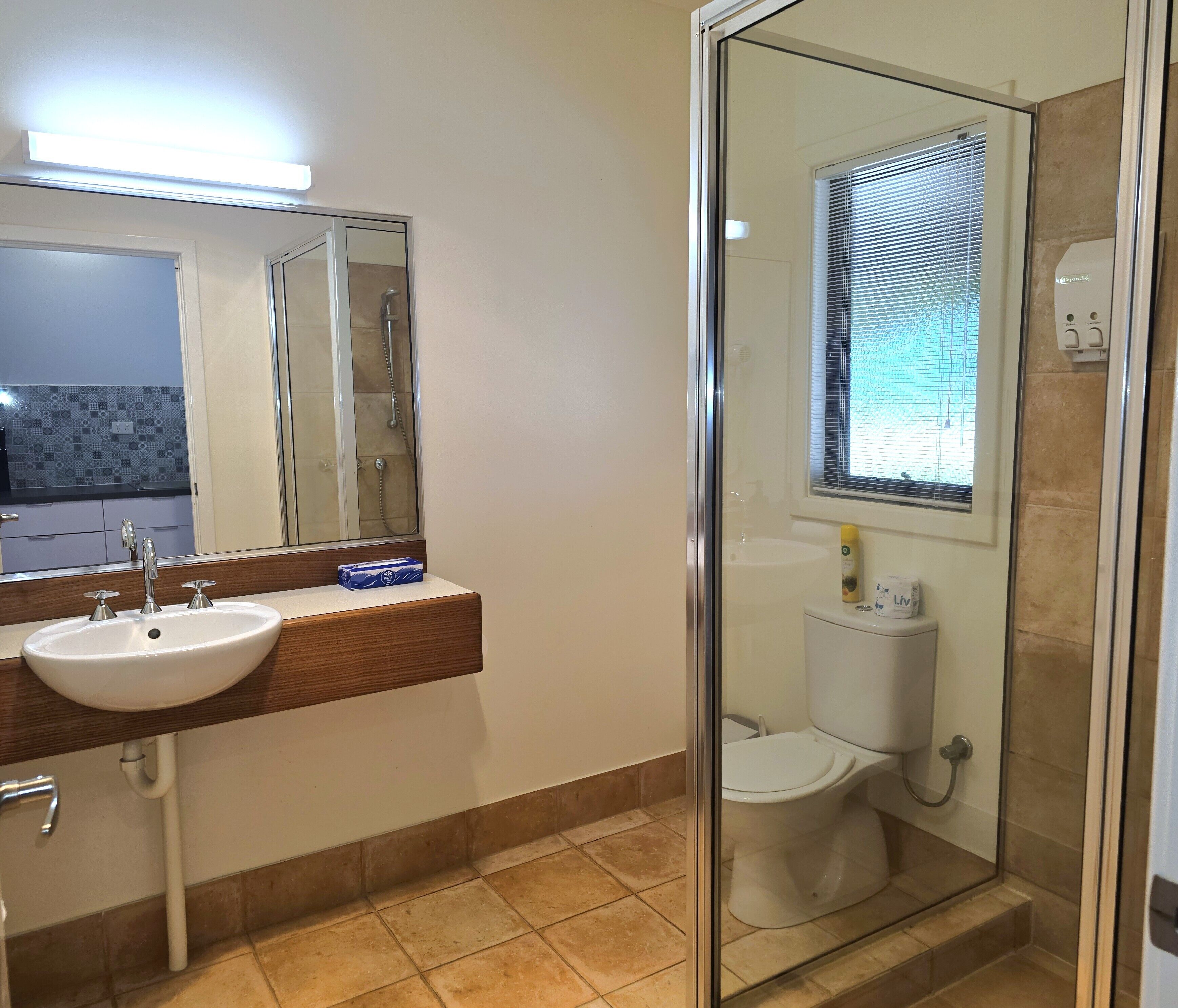 A bathroom with a glass-enclosed shower, a sink with a mirror, and a toilet.
