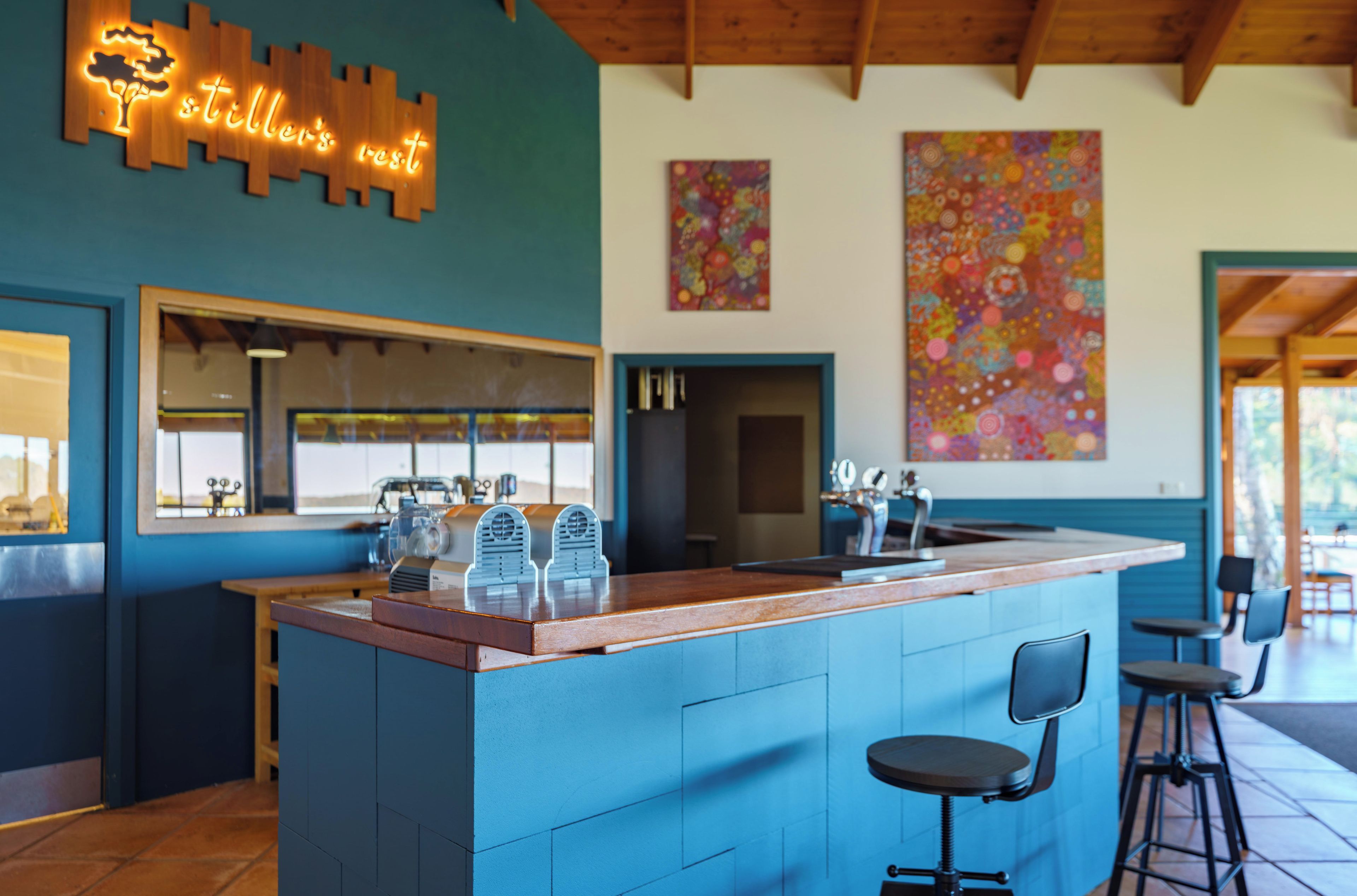 A bar area with a wooden sign, a counter, and bar stools.