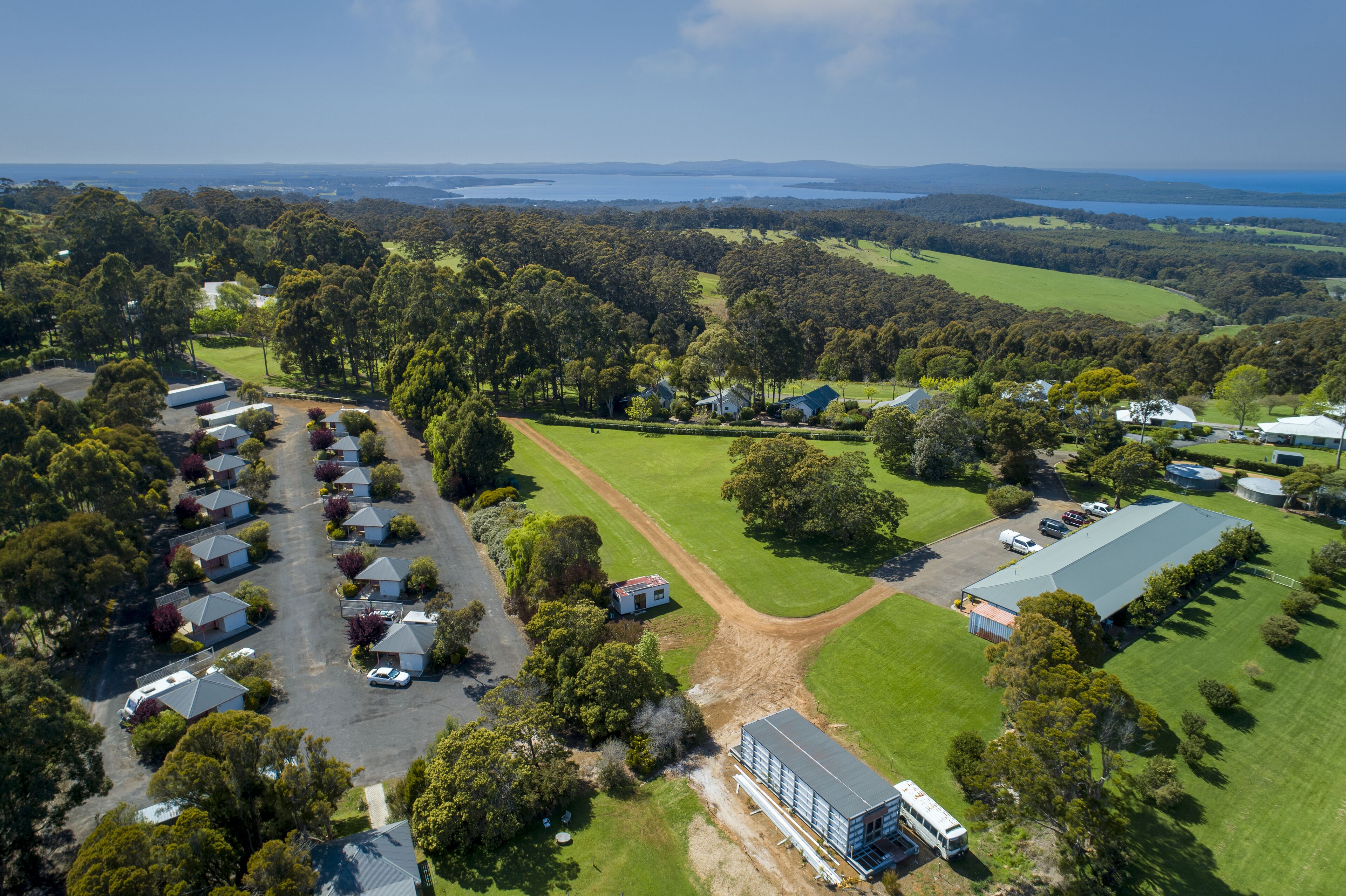 An aerial view of a residential area with houses, a large building, and a body of water in the background.