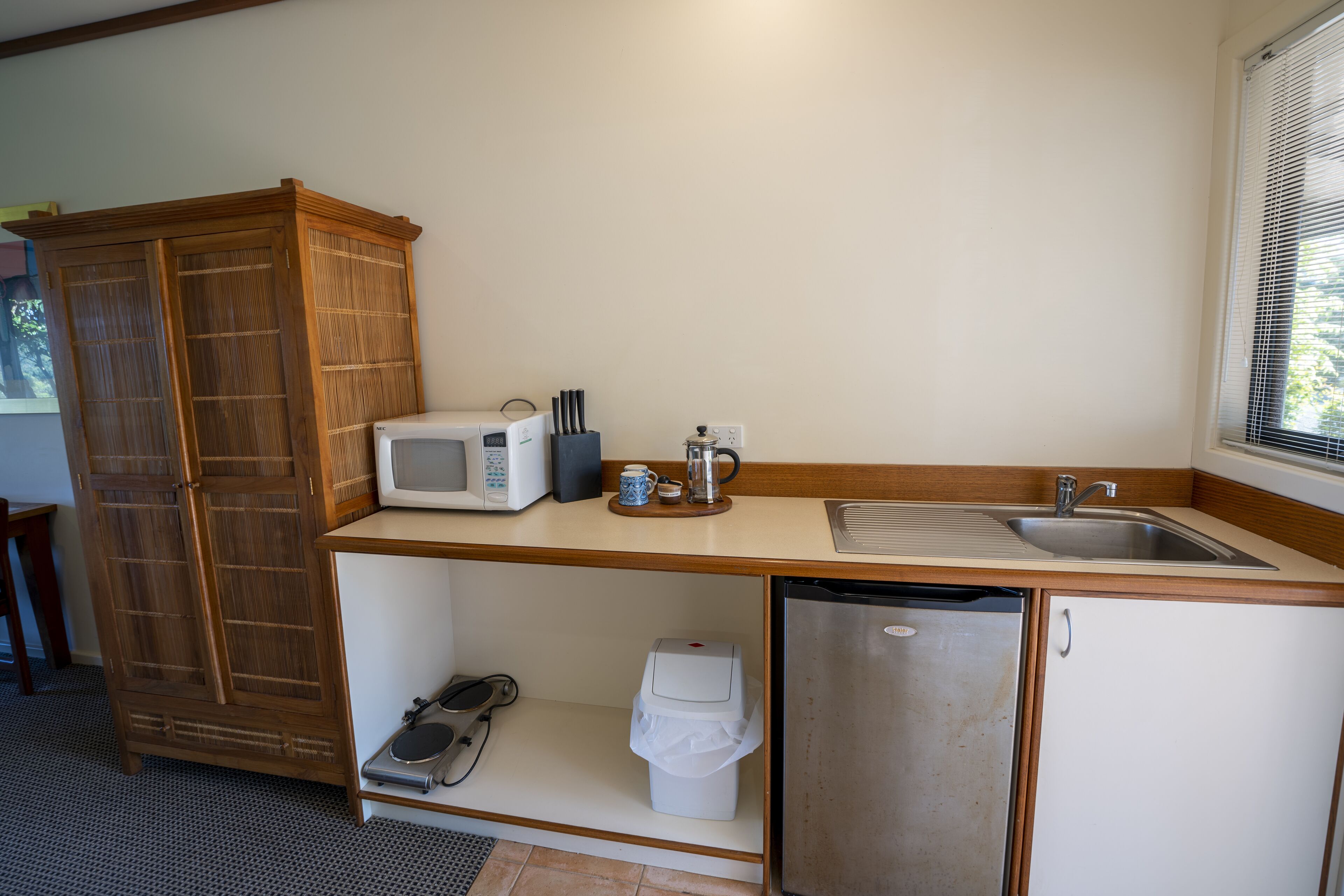 A compact kitchen with a microwave, coffee maker, and sink.