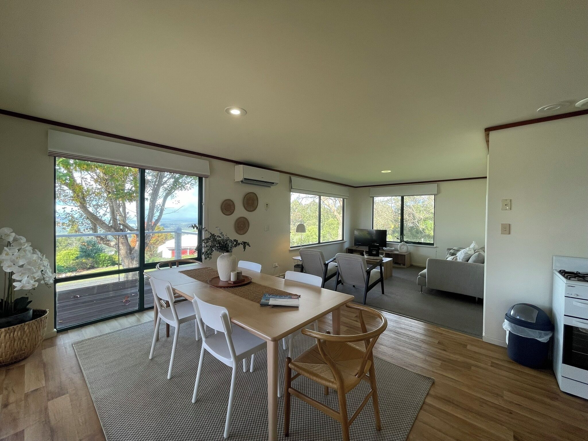 A spacious living area with a dining table, chairs, a sofa, and a TV.