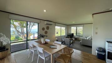 A spacious living area with a dining table, chairs, a sofa, and a TV.