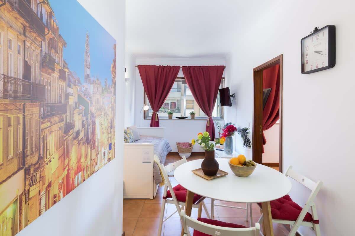 A cozy room with a dining table, chairs, a clock, and a window with curtains.