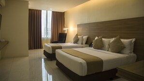 A hotel room with two beds, a desk, and a chair.