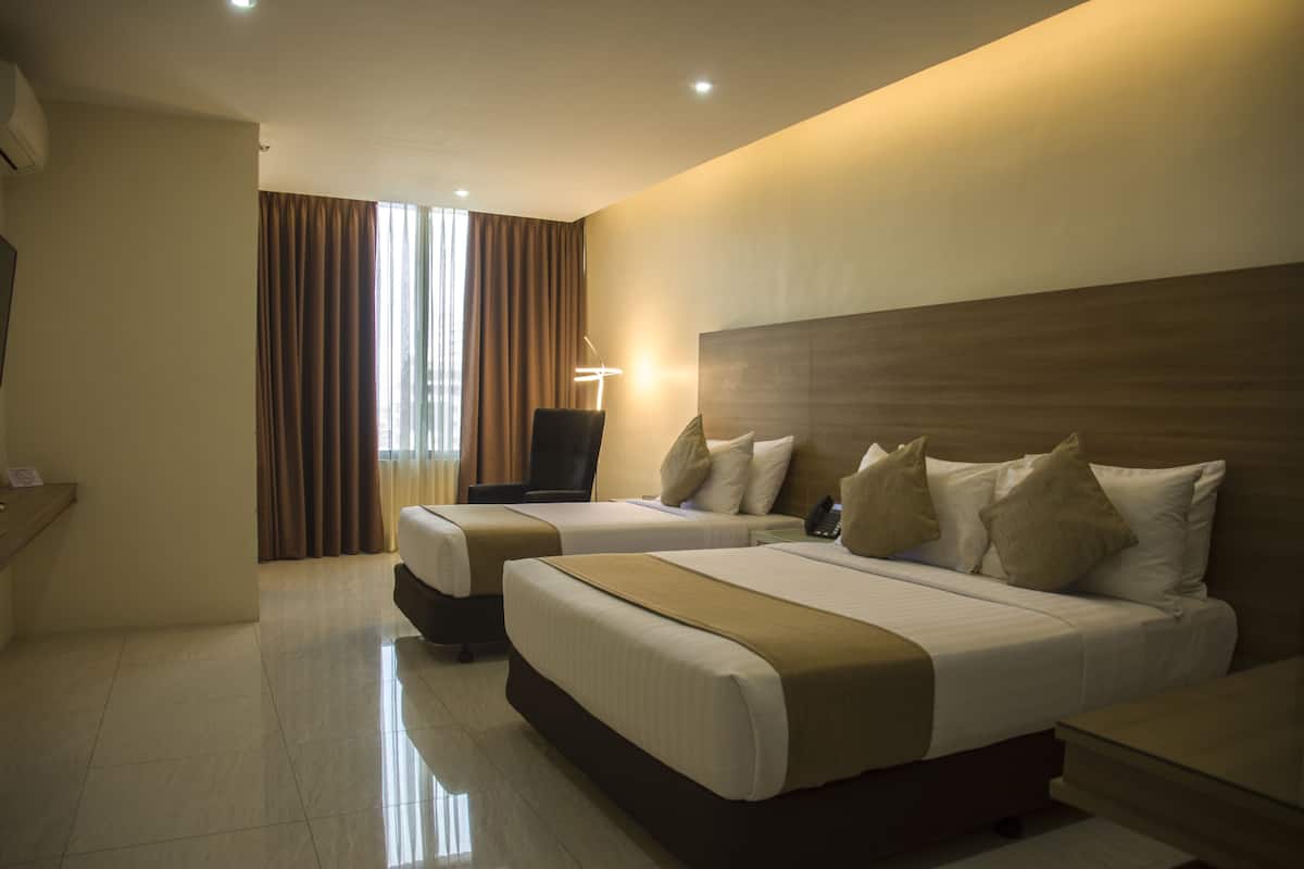 A hotel room with two beds, a desk, and a chair.