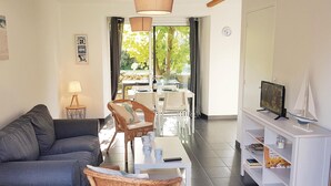 Een woonkamer met een bank, een eettafel met stoelen, een televisie en een boekenkast.