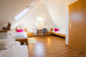 Un dormitorio de ático acogedor y bien iluminado, con techo inclinado, tragaluz, escritorio y cama.