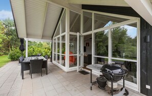 A covered patio with a dining table and chairs, a barbecue grill, and a glass door leading to an interior space. - 3 bedroom beautiful home in Glesborg (Glesborg)