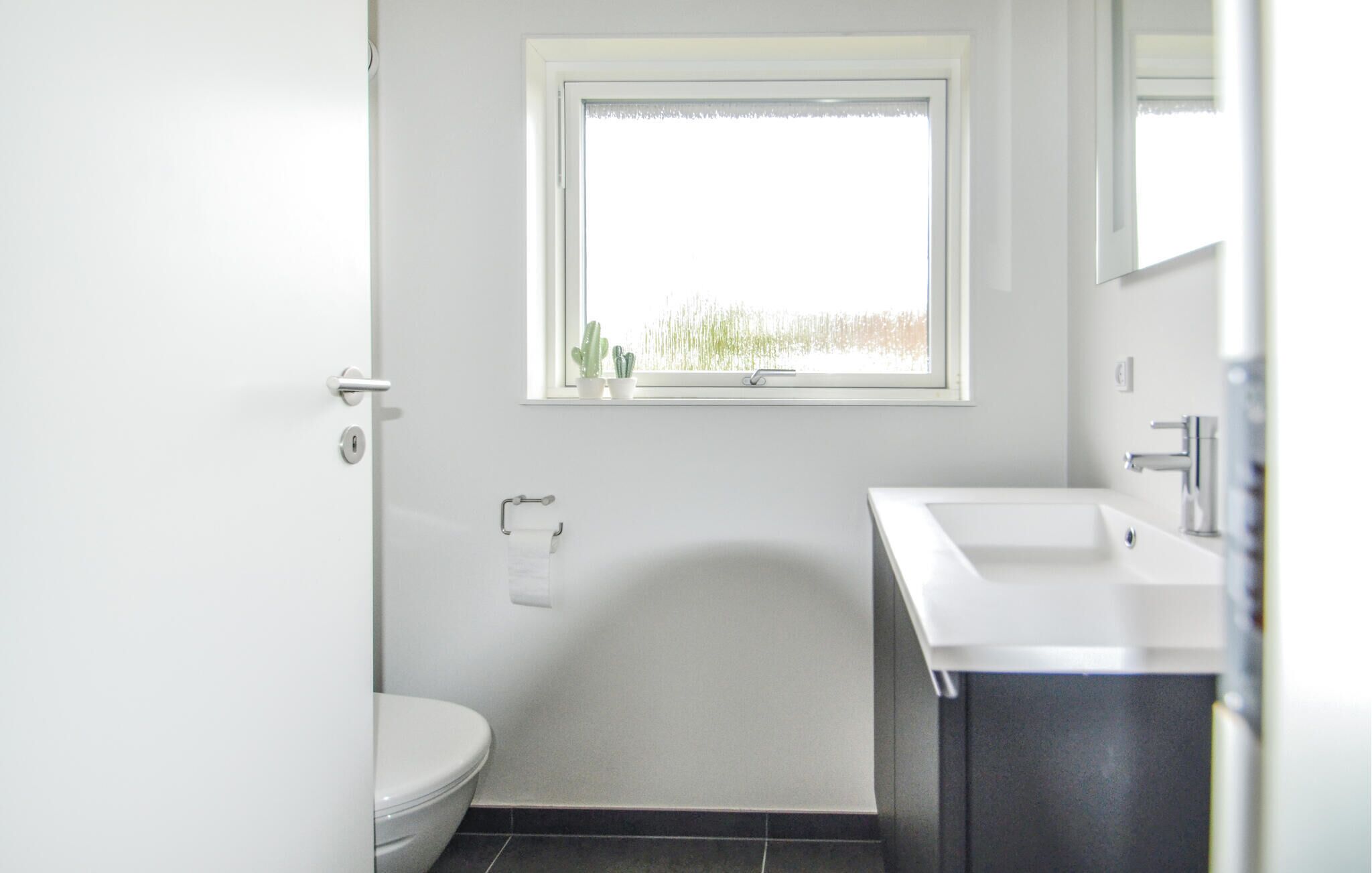 Une petite salle de bain moderne, équipée de toilettes, d’un lavabo et d’une fenêtre.