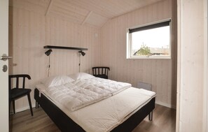 A bedroom with a bed, two chairs, a window, and a wooden ceiling. - 3 bedroom beautiful home in Glesborg (Glesborg)