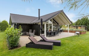 A house with a covered patio, outdoor furniture, and a garden. - 3 bedroom beautiful home in Glesborg (Glesborg)