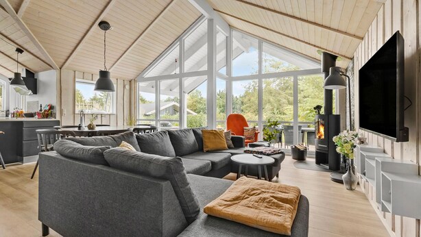 A spacious living room with a large gray sectional sofa, a round coffee table, and a fireplace. - 3 bedroom beautiful home in Glesborg (Glesborg)