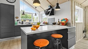 A modern kitchen with a large island, black bar stools, pendant lighting, and a view of the outdoors. - 3 bedroom beautiful home in Glesborg (Glesborg)