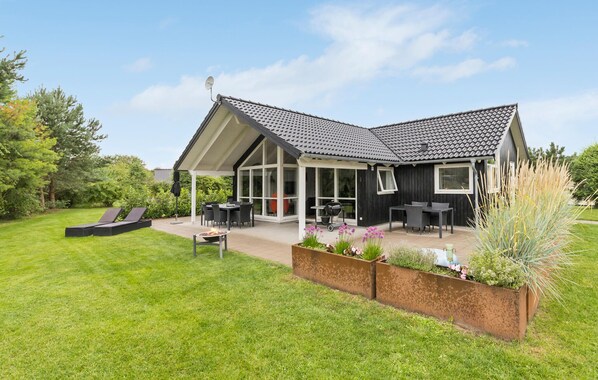 A modern house with a covered patio, a lawn, and a garden with various plants. - 3 bedroom beautiful home in Glesborg (Glesborg)