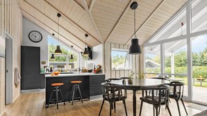 A modern kitchen with a large island, bar stools, and a dining area with a table and chairs. - 3 bedroom beautiful home in Glesborg (Glesborg)