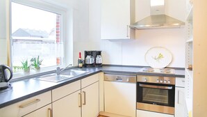 Una cocina moderna con lavavajillas, horno y una ventana con plantas en la encimera.