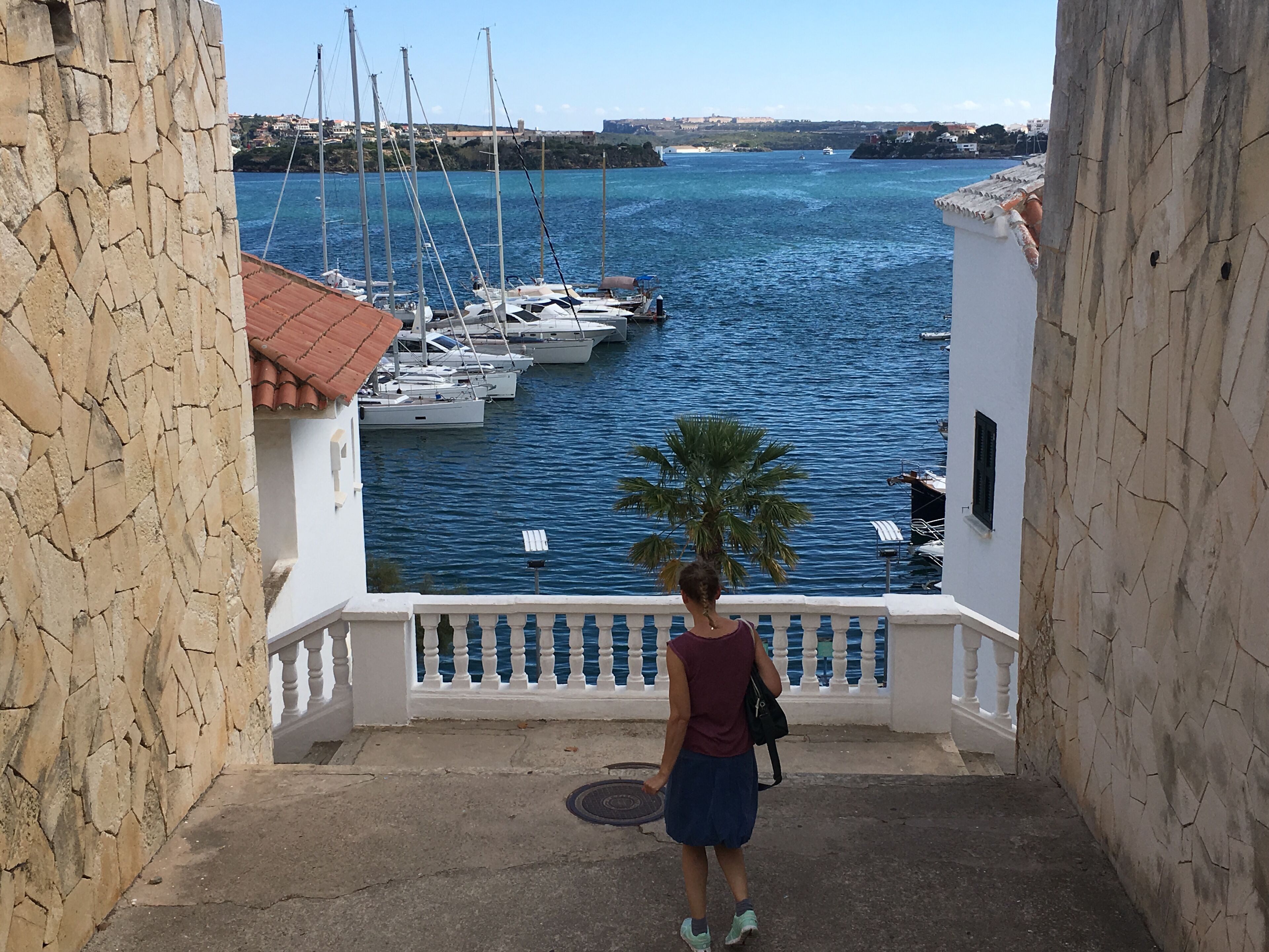 Una mujer está de pie en un balcón con vista a un puerto deportivo con barcos.
