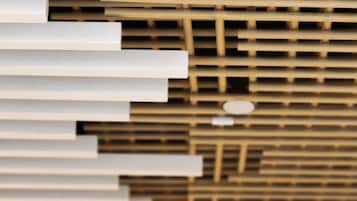 A modern interior with a wooden slatted ceiling and white horizontal beams.