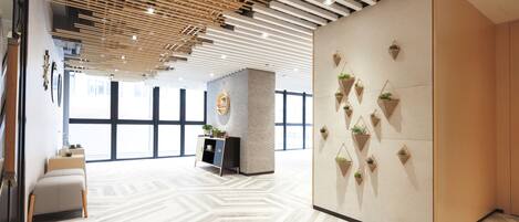A modern interior with a geometric patterned floor, a wooden slatted ceiling, and a wall adorned with hanging planters.