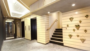 Un interior moderno con una escalera, un diseño geométrico en el techo y macetas colgantes en la pared.
