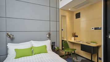 A modern hotel room with a bed, a desk, and a chair.