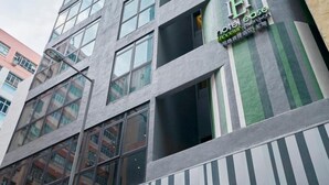 Un moderno edificio de hotel con un diseño vertical llamativo, grandes ventanales y un letrero que indica que es un hotel.