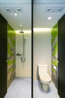 Un baño moderno con ducha, inodoro y estante con artículos de aseo.