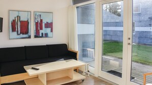 A modern living room with a black sofa, a light wooden coffee table, and two abstract paintings on the wall. - Amazing apartment in Løgumkloster (Løgumkloster)