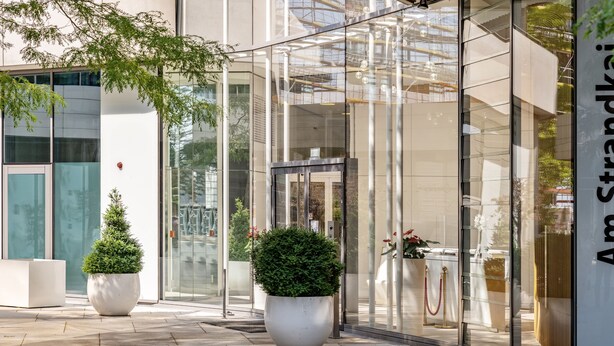 A modern building with large glass windows, a reception area, and potted plants. - Marco Polo Tower, Hafencity, pure luxury, air conditioning, harbor view, (Hamburg)