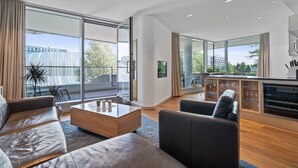 A modern living room with a sofa, coffee table, and a glass cabinet with wine glasses. - Marco Polo Tower, Hafencity, pure luxury, air conditioning, harbor view, (Hamburg)