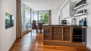 A modern kitchen with a wooden island, glass cabinets, and a built-in wine cooler. - Marco Polo Tower, Hafencity, pure luxury, air conditioning, harbor view, (Hamburg)