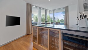A modern kitchen with a large island, glass cabinets, and a built-in oven. - Marco Polo Tower, Hafencity, pure luxury, air conditioning, harbor view, (Hamburg)