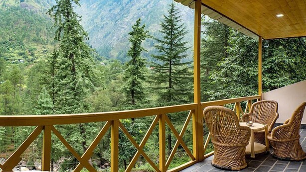 A balcony with wicker furniture overlooking a mountainous landscape. - Parvati Kuteer (Bhuntar)