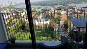 A balcony with a view of a river, residential buildings, and a cityscape in the distance. - Riverfront Osis Resort Balcony (Ho Chi Minh City)