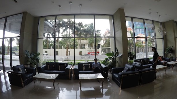 A spacious lobby with large windows, leather sofas, and a clean tiled floor. - Riverfront Osis Resort Balcony (Ho Chi Minh City)