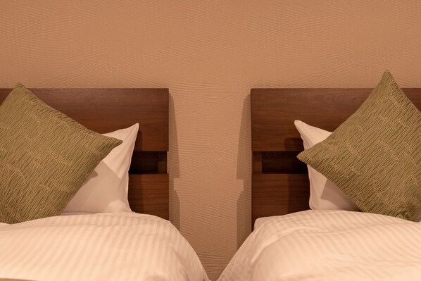 A mirrored view of a double bed with green and white pillows, a wooden headboard, and a textured wall. - Kyoto Riverview House Kyou-raku (Kyoto)