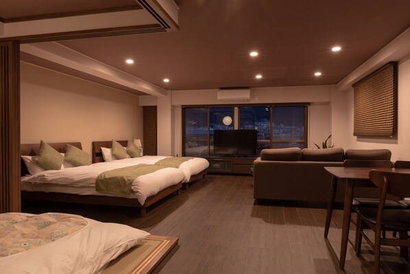 Una habitación de hotel moderna con una cama grande, un sofá, una televisión y vistas a la ciudad.