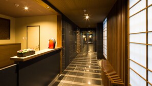 A hotel corridor with a reception desk, a wooden bench, and a tiled floor. - Kyoto Riverview House Kyou-raku (Kyoto)