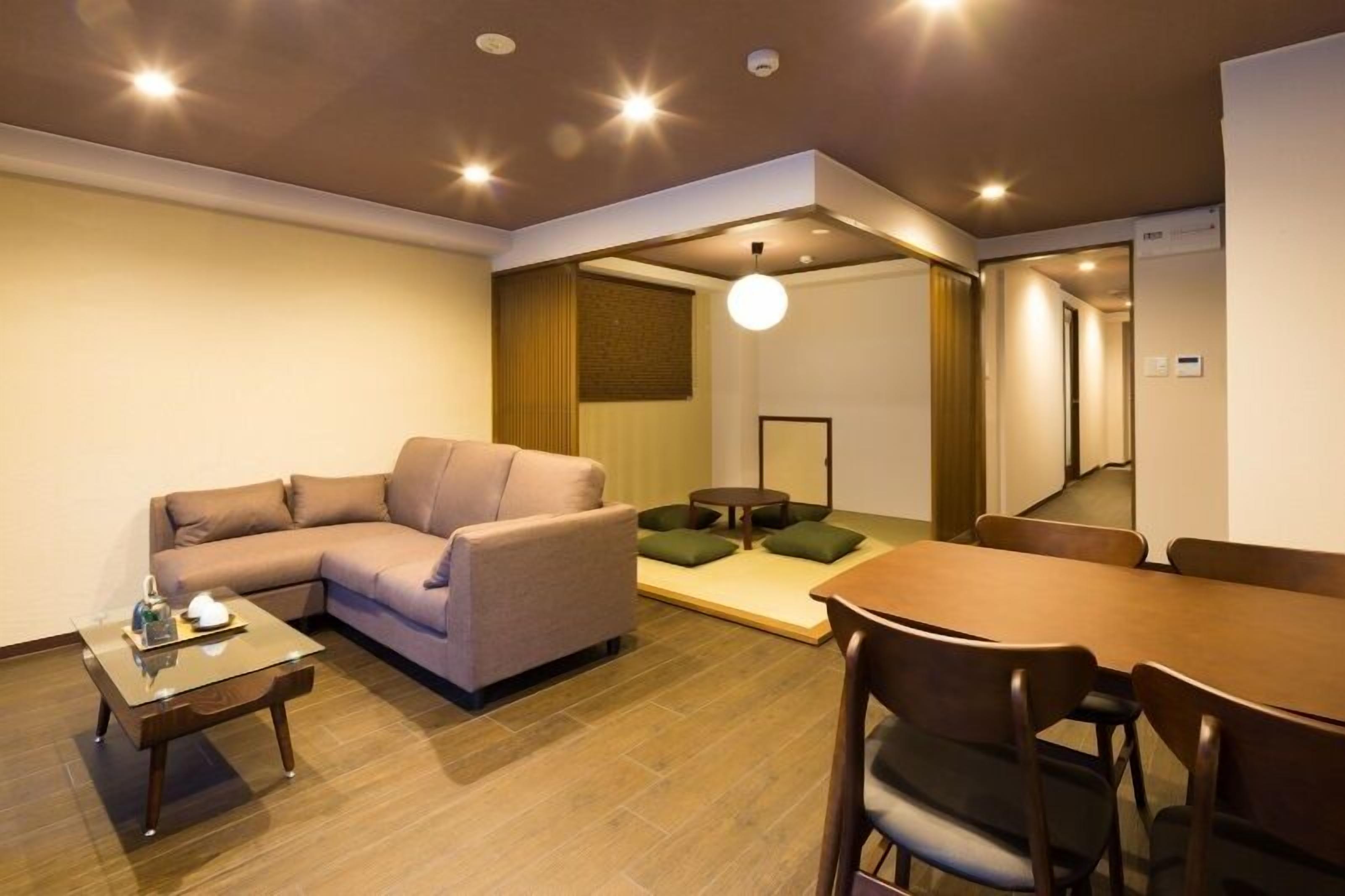 A modern hotel room with a sofa, a dining table, and a small coffee table.