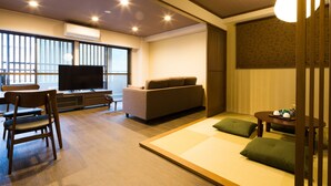A modern living room with a sofa, a TV, and a dining area. - Kyoto Riverview House Kyou-raku (Kyoto)