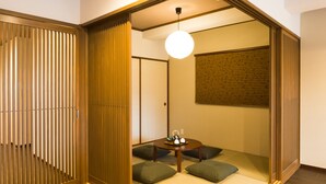 A traditional Japanese-style room with tatami flooring, a low table with cushions, and sliding doors. - Kyoto Riverview House Kyou-raku (Kyoto)