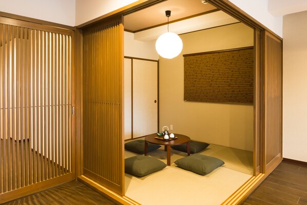 A traditional Japanese-style room with tatami flooring, a low table with cushions, and sliding doors.