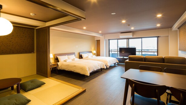 A hotel room with a large bed, a TV, a sofa, and a dining table. - Kyoto Riverview House Kyou-raku (Kyoto)