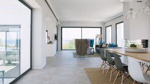 Eine moderne Küche mit Essbereich, großen Fenstern und Blick ins Freie.