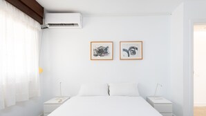 A minimalist bedroom with a large bed, two bedside tables, a nightstand, and two framed pictures on the wall. - Over the Ocean with pool (Candelaria)